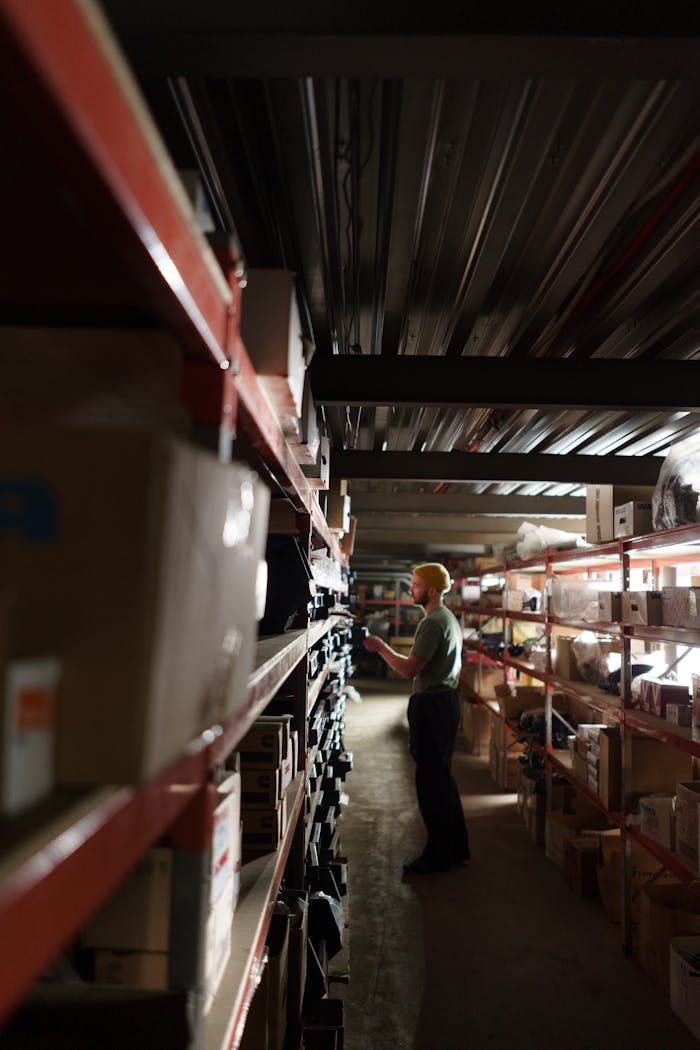 A worker organizing shelves in a dimly lit warehouse environment.